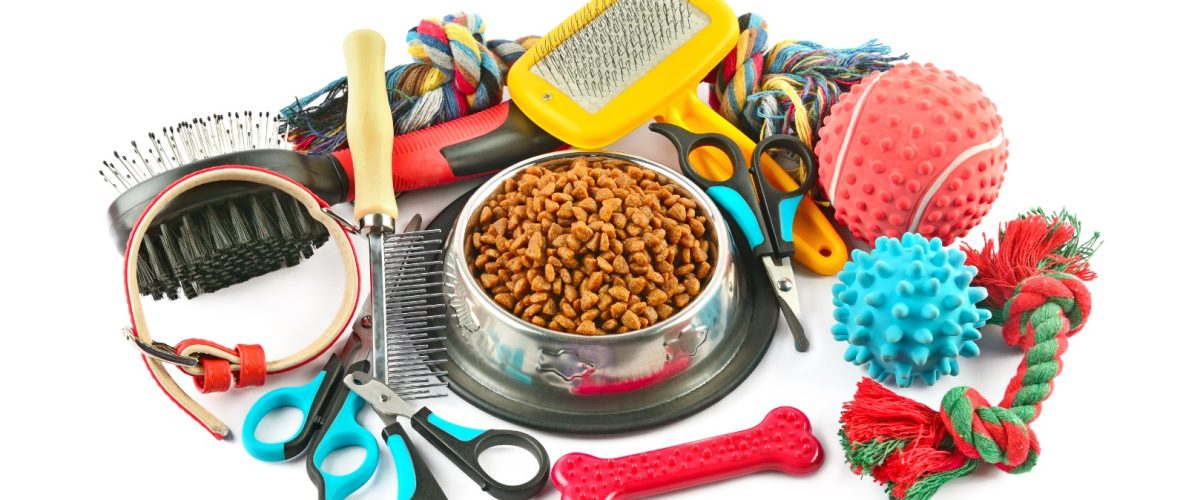 Pet accessories concept. Dry food, collars and rubber toys for pet on isolated white background.